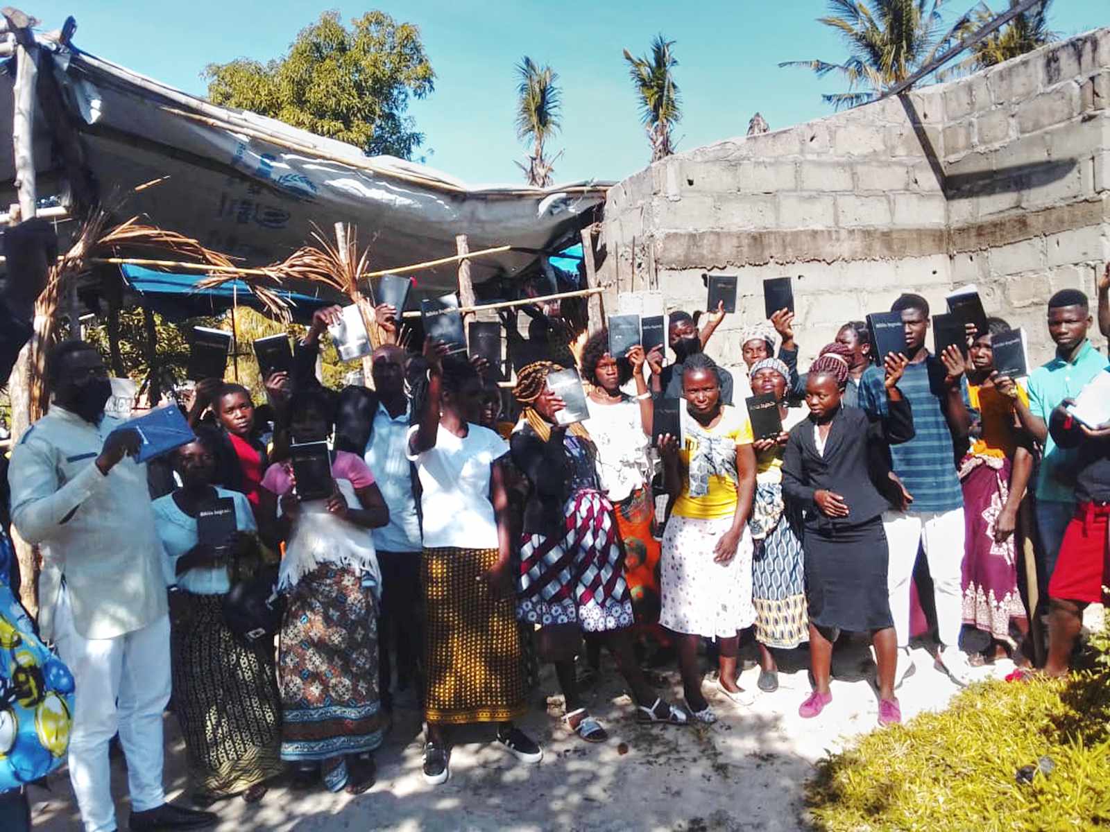 Believers holding up their new Bibles together at a rural village in Mozambique