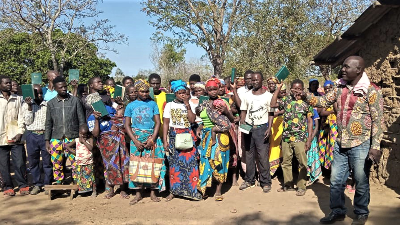 Abel with villagers holding up their new Bibles at a remote rural village in Mozambique