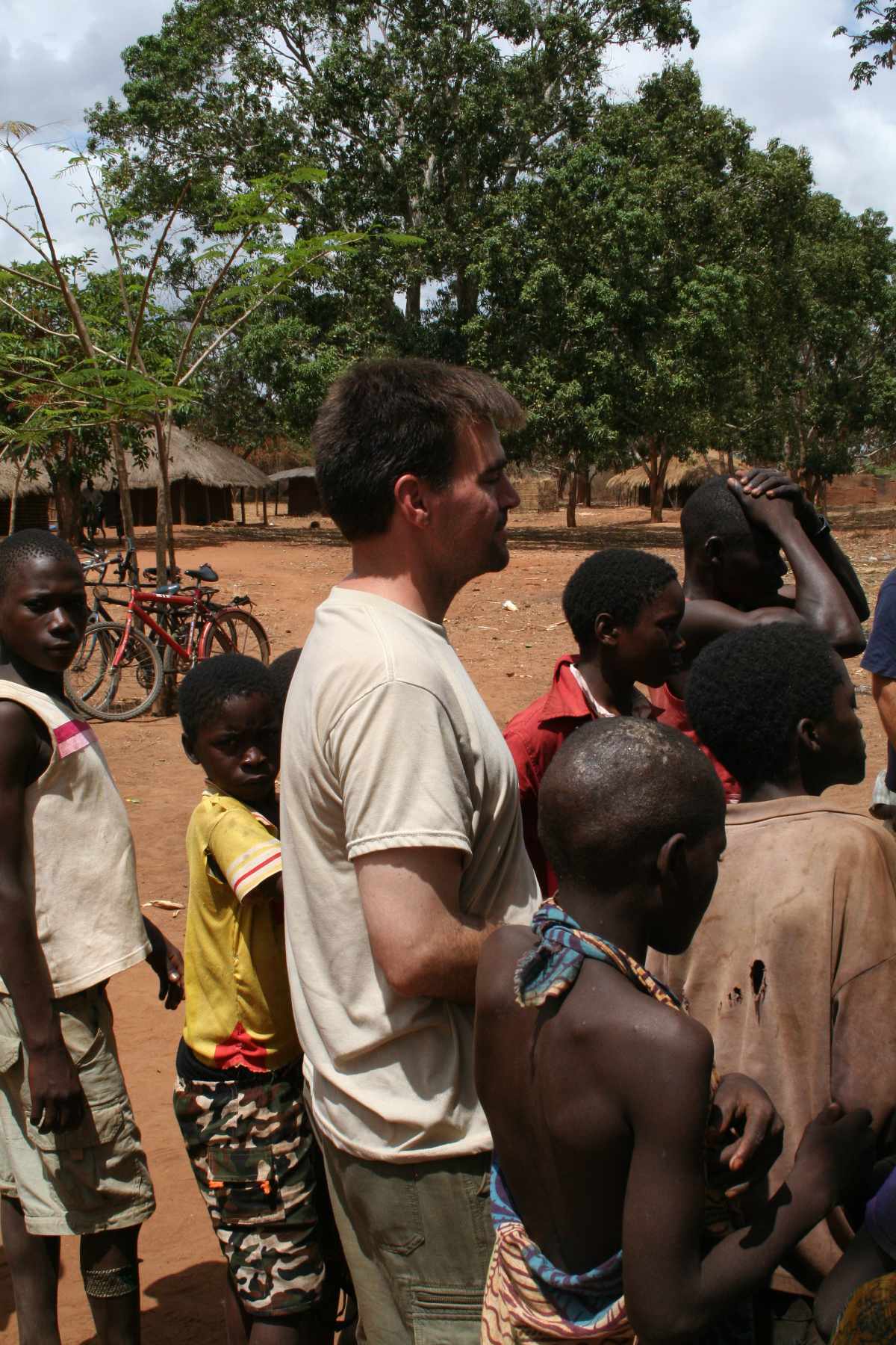 Jason standing among some children during a multi-day ministry outreach in a remote village in Cabo Delgado Province, Mozambique, while he and Susan were attending missions school in 2009 — Susan behind the camera.