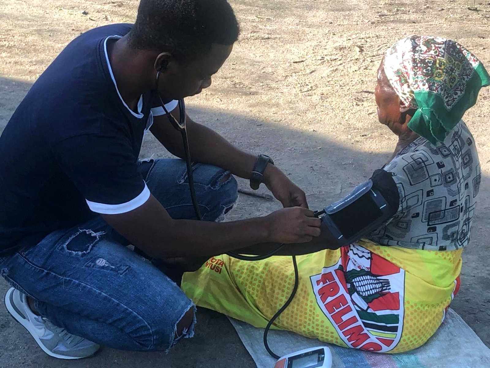 Lourenço, one of our medical team members, checking an elderly woman's blood pressure during a home visit in rural Mozambique