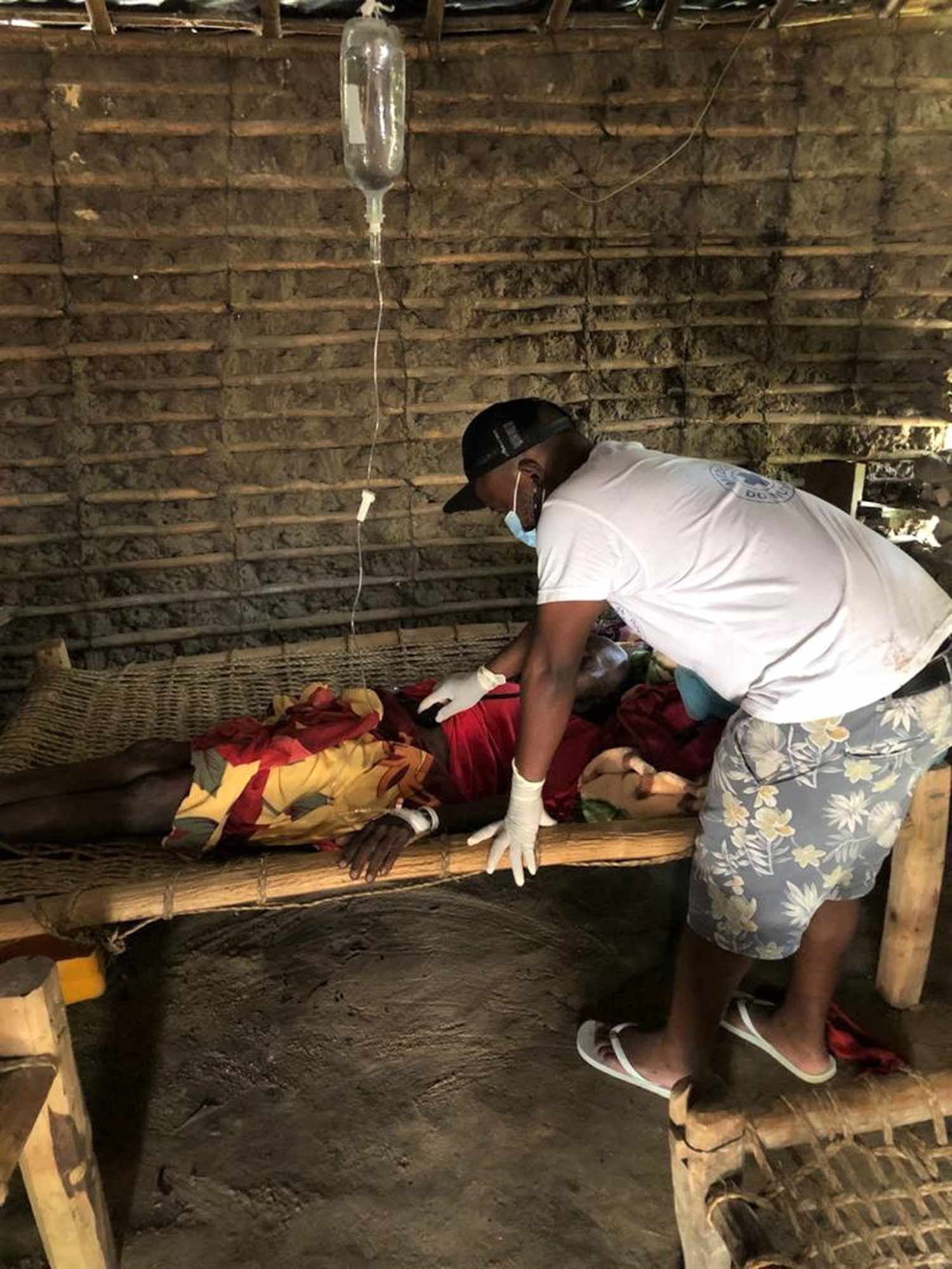 Dr. Vladimir, one of our former medical team members, treating a bedridden patient on an intravenous drip during a home visit in rural Mozambique