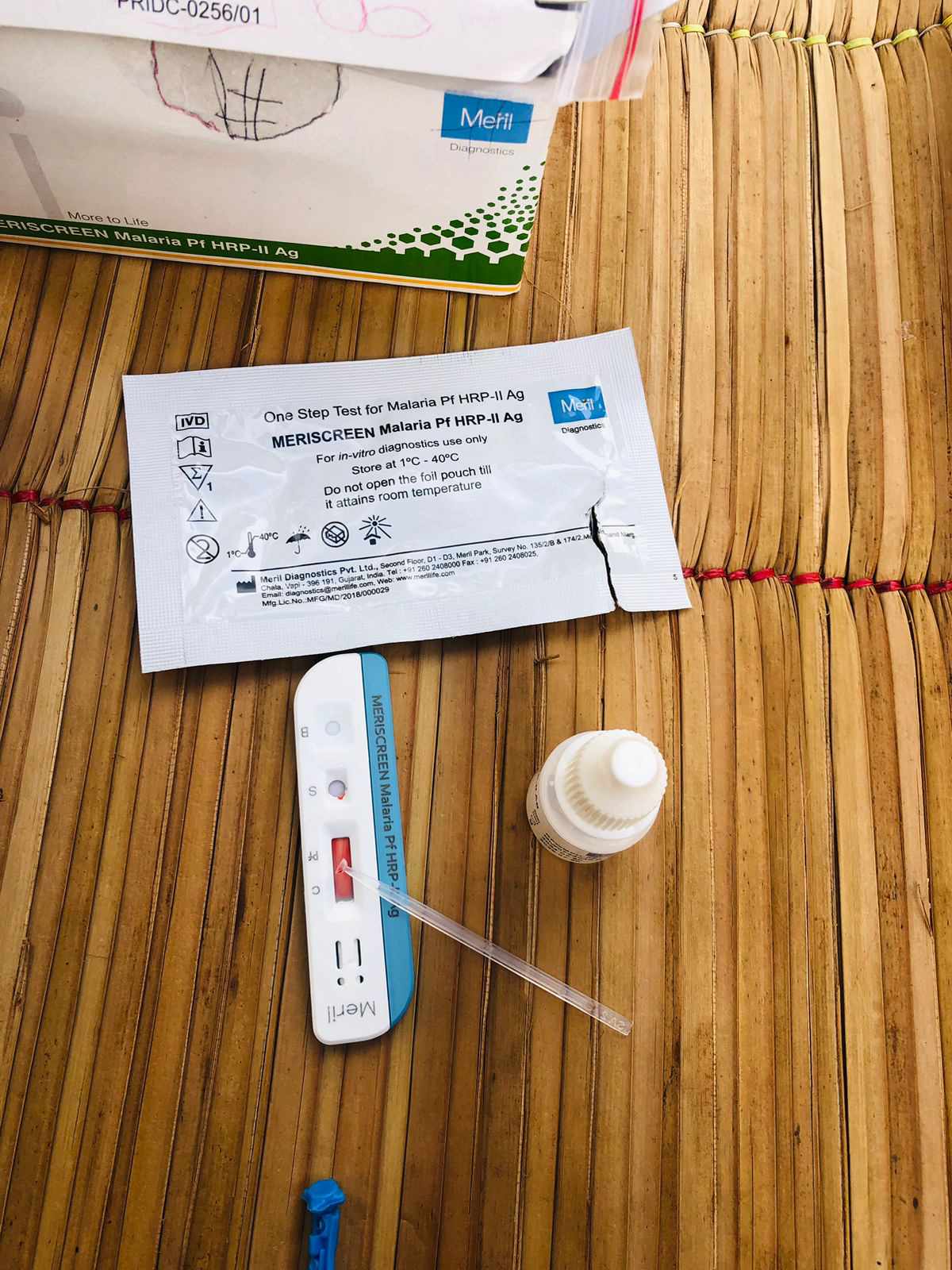 A rapid malaria test kit and medical supplies laid out during a home visit in rural Mozambique