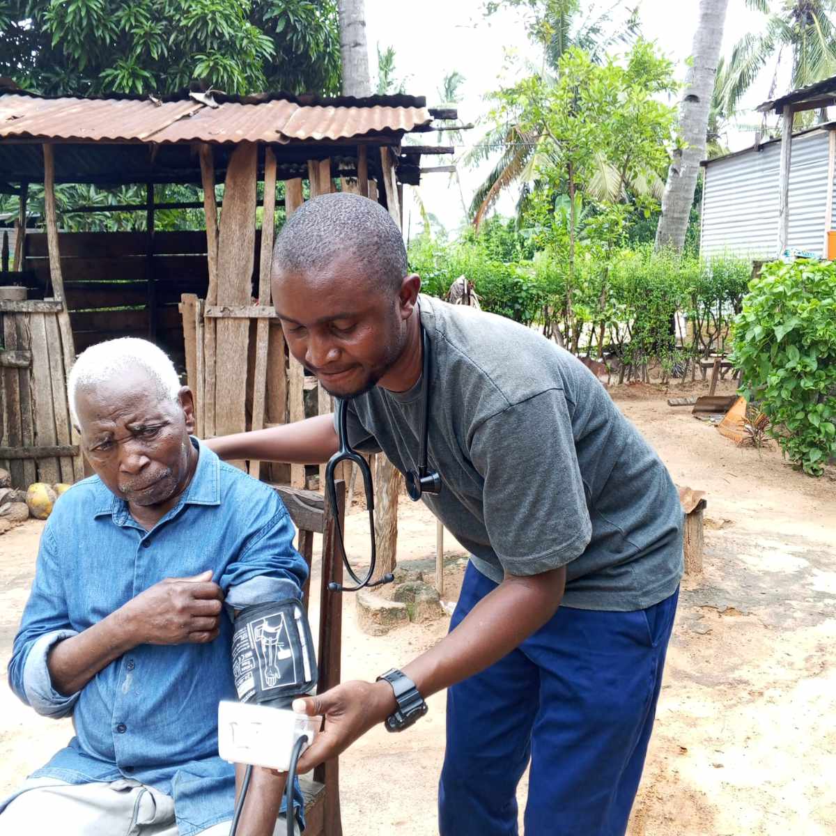 Jossias, one of our medical team members, checking an elderly man's blood pressure during a home visit in rural Mozambique